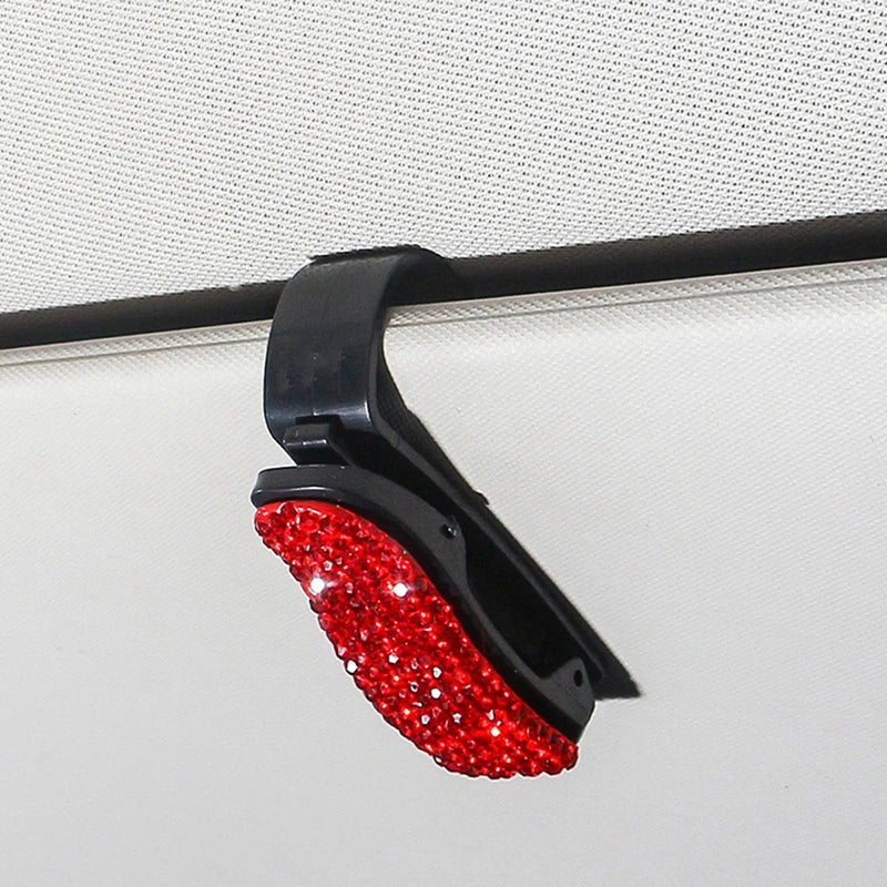 Black clip with red rhinestones used to secure a car sun visor or sunglasses.