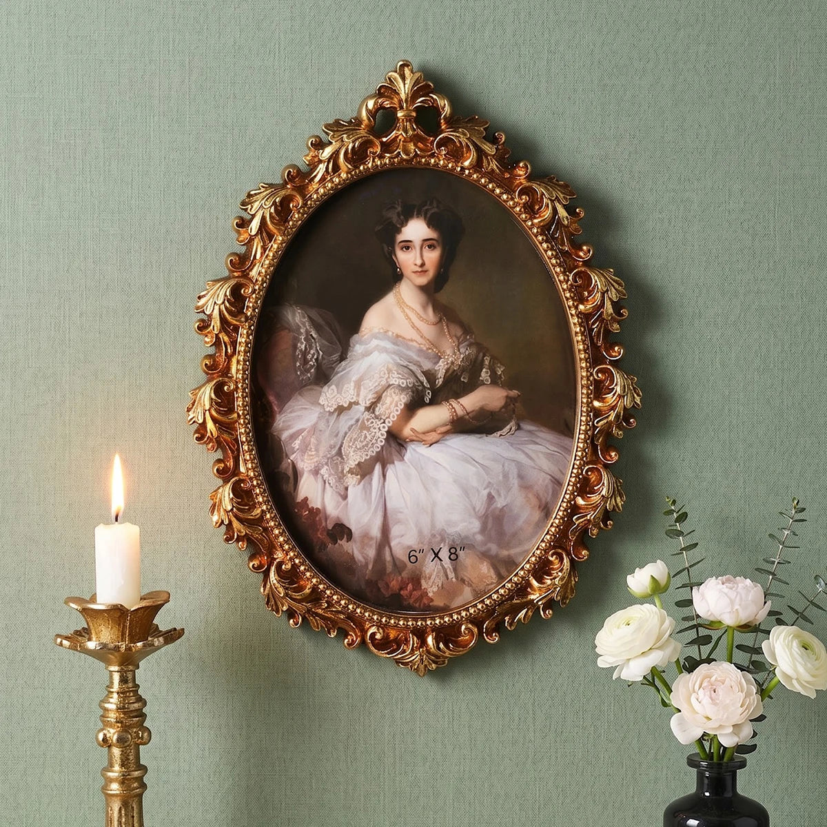 An ornate gold-framed portrait of a woman with white lace and flowing dress hanging on a green wall.