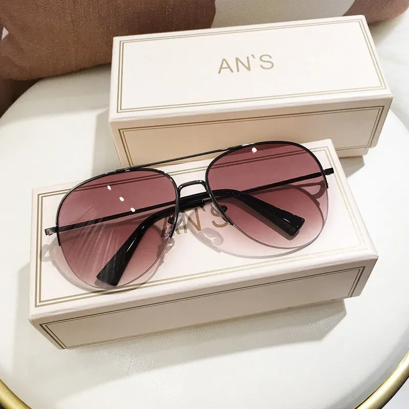 Eine braun getönte Aviator-Sonnenbrille liegt in einer weißen Box mit der Aufschrift AN'S
