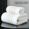 A stack of white bath and hand towels with gold stripes displayed on a dark surface.