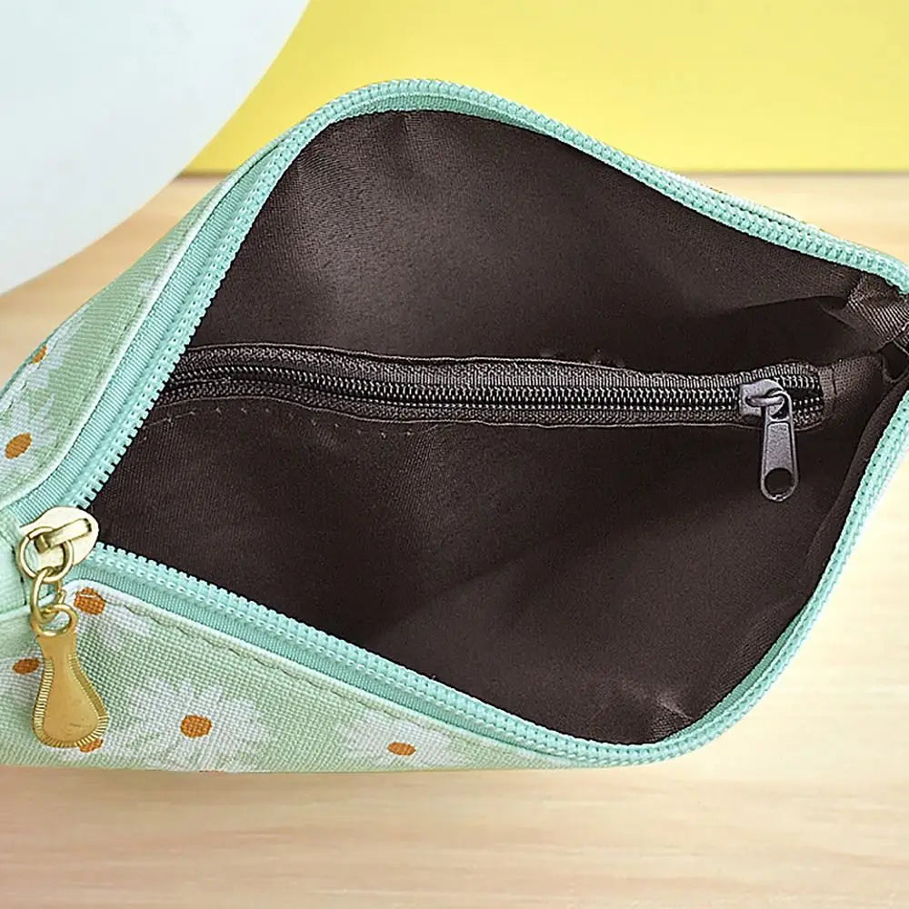 A light green PU leather wristlet wallet with a zipper closure and daisy print pattern shown open.