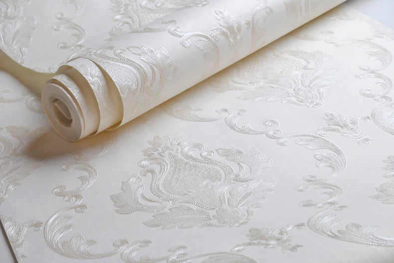 Roll of embossed damask wallpaper featuring a textured floral design on a white background.
