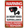 A vintage metal tin sign with a red background and white text warning about 24 hour video surveillance and private property n
