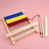 A wooden weaving loom kit with blue, yellow, and red yarn is displayed on a pink background.
