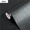 Roll of black embossed silk self-adhesive wallpaper being peeled from its roll.