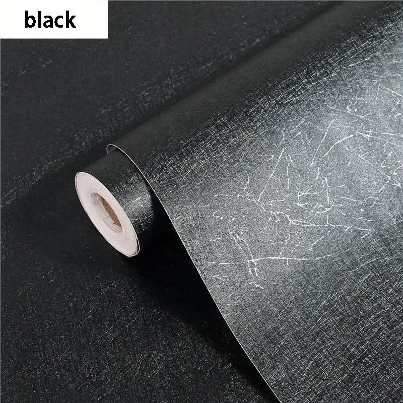 Roll of black embossed silk self-adhesive wallpaper being peeled from its roll.