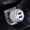 A close-up of a rhinestone dual USB car charger with blue accents inserted into a black device slot.