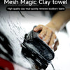 A hand is using a black mesh clay towel to clean mud stains from a car's paint surface.