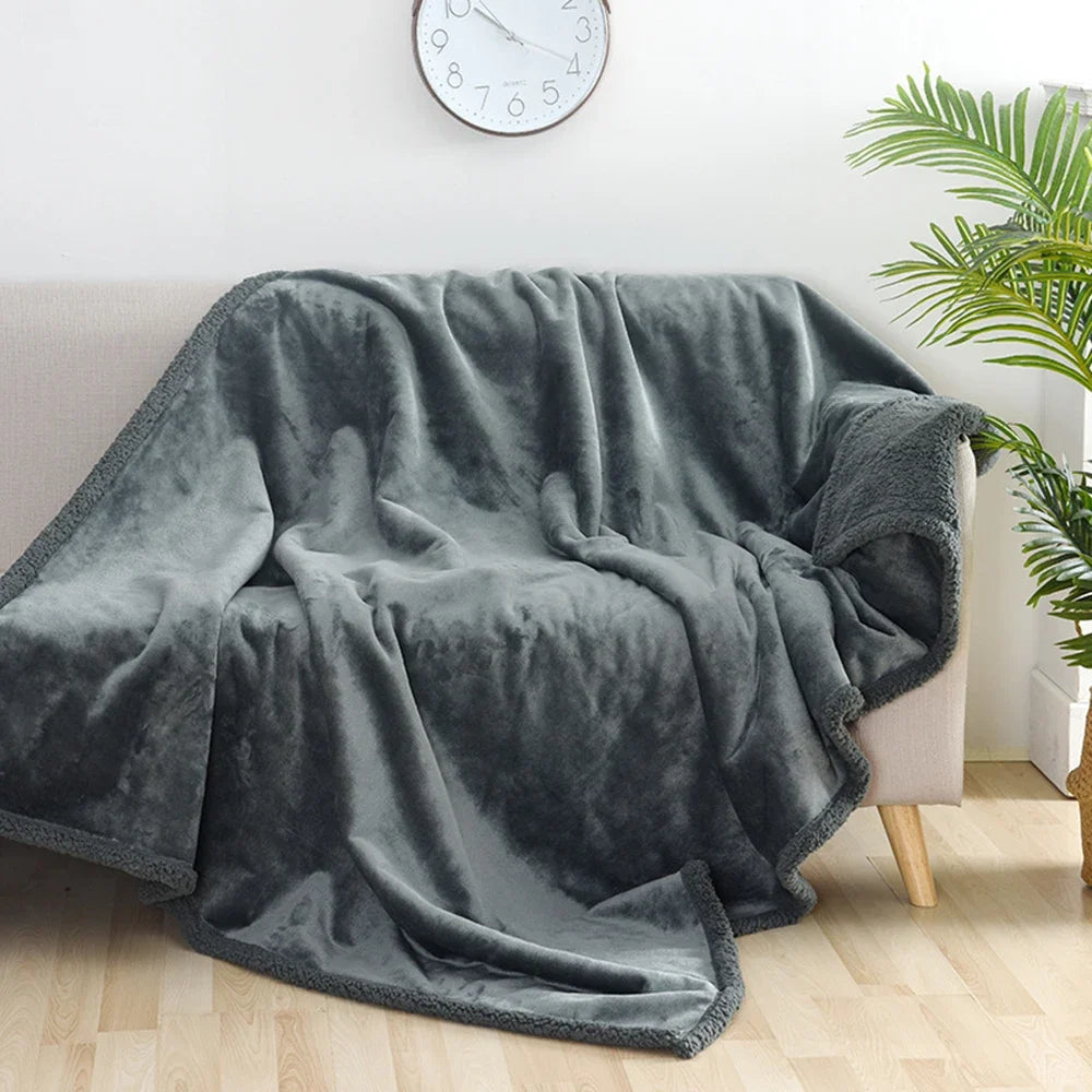 A dark gray faux fur throw blanket draped over a light-colored sofa.