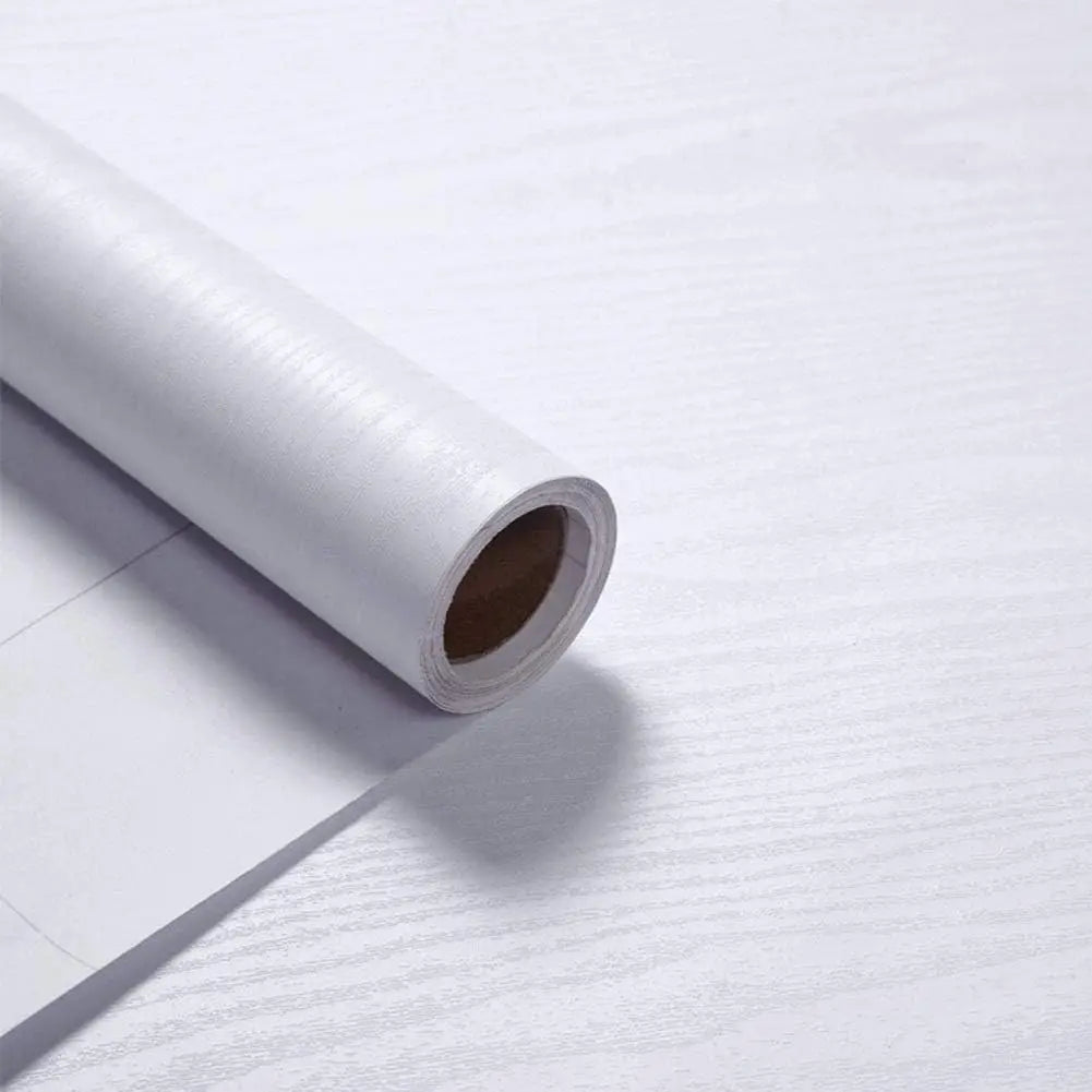 A roll of self-adhesive wood grain waterproof wallpaper lying on a white surface.
