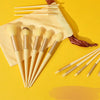 A set of thirteen makeup brushes and a brown travel bag are displayed on a yellow background.