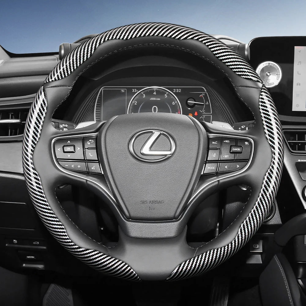 A close-up view of a black steering wheel with a carbon fiber texture cover and controls inside a car interior.