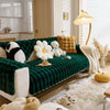 Tiefgrüner Plüschhase-Sofa-Kissen mit weißen und beigen Kunstfellakzenten auf hellem Holzfußboden.
