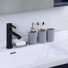 A set of four bathroom accessories including a black soap dispenser, holder, and two toothbrushes on a white sink.