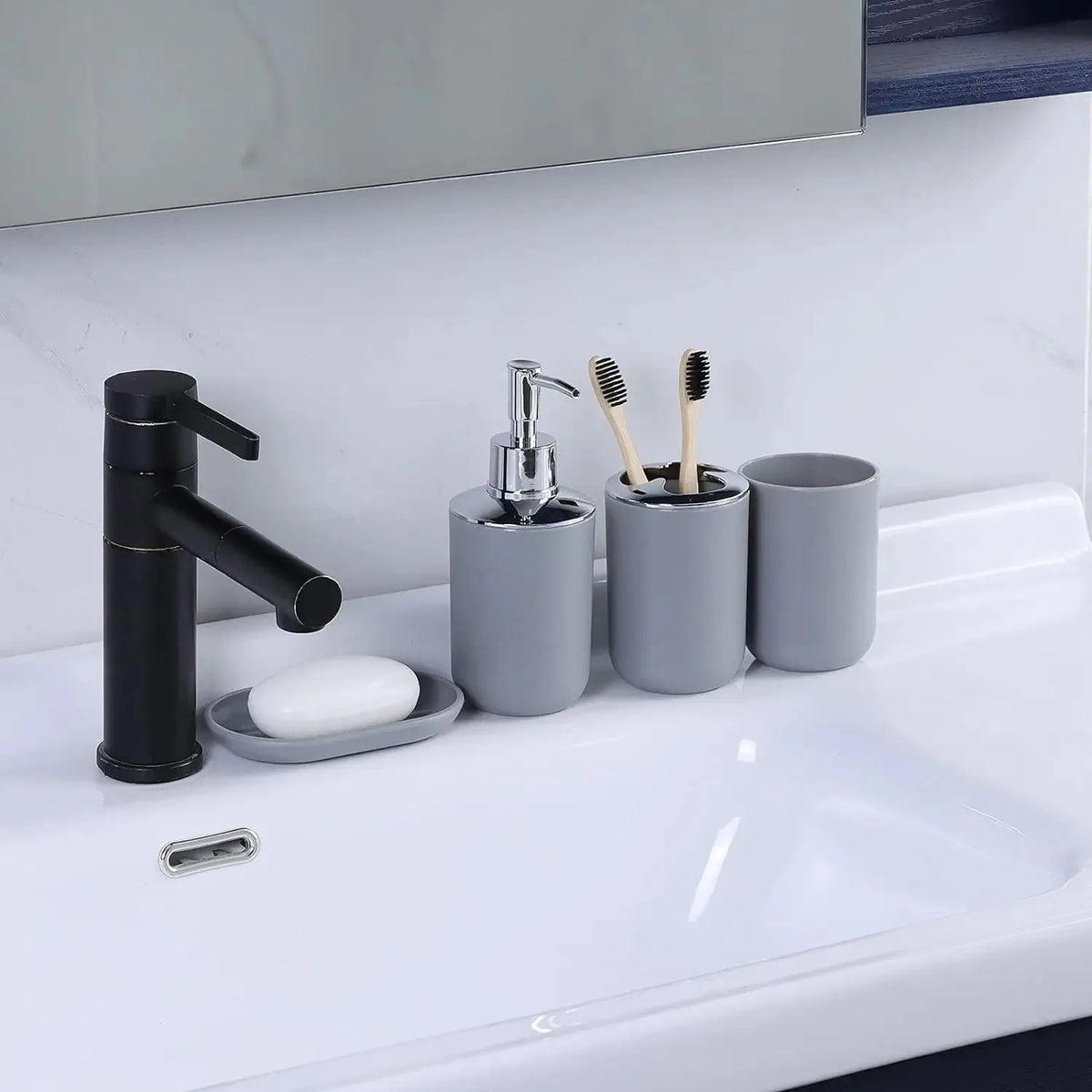 A set of four bathroom accessories including a black soap dispenser, holder, and two toothbrushes on a white sink.