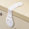 White child safety cabinet lock with a strap and release mechanism installed on a wooden drawer or cabinet.
