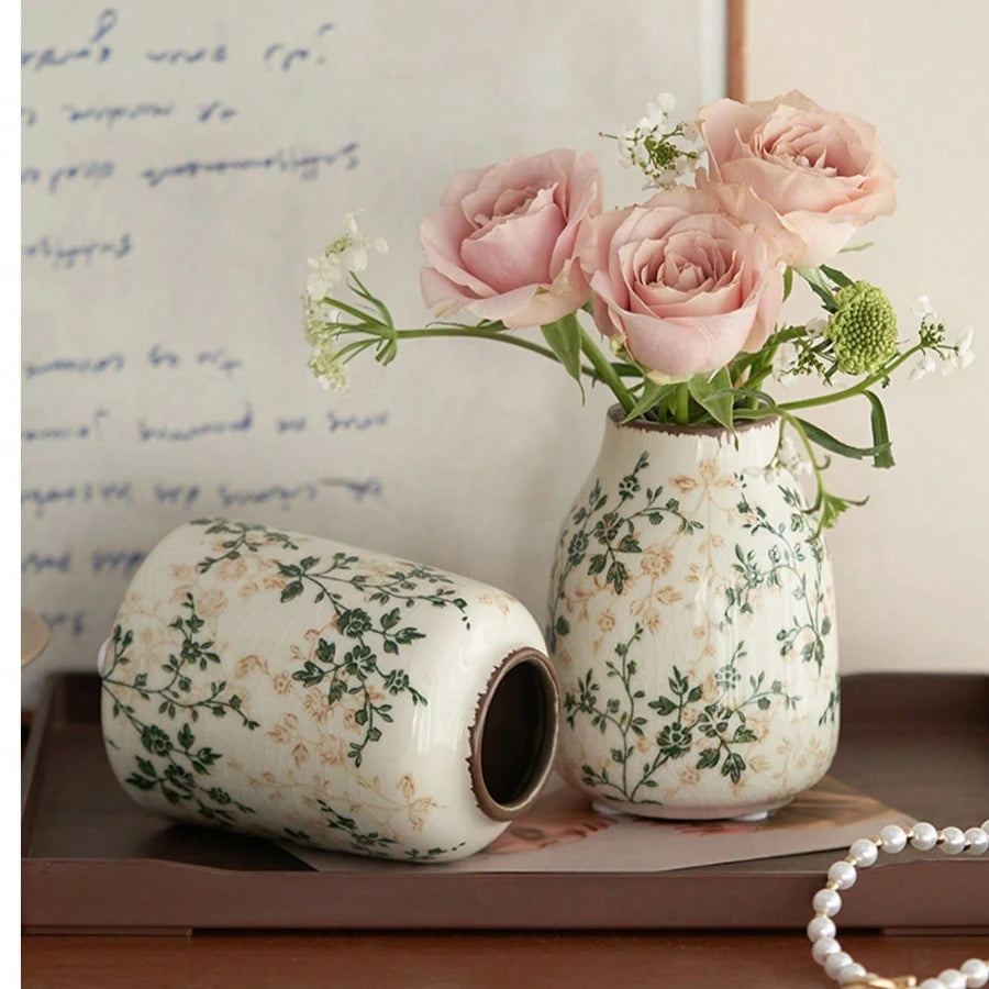 Handgemachte, gesplitterte Keramikvase mit rosa Rosen auf Holzoberfläche.