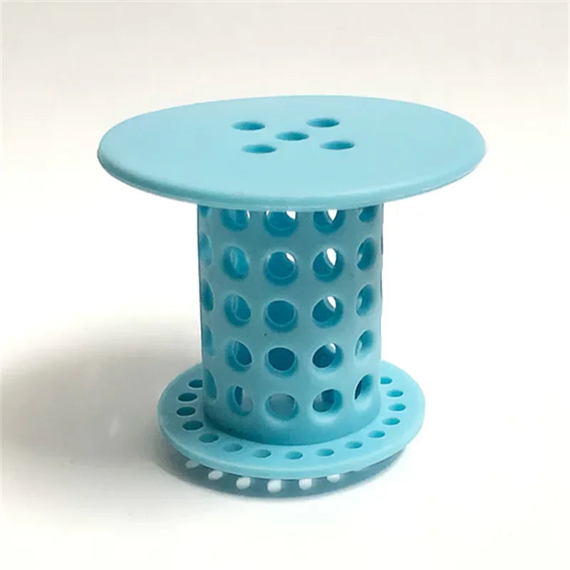 A light blue flexible hair catcher drain cover with a perforated top and base for sinks and tubs.