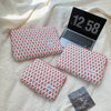 A floral printed laptop sleeve in red and green is shown next to an open laptop displaying the time 12:58.