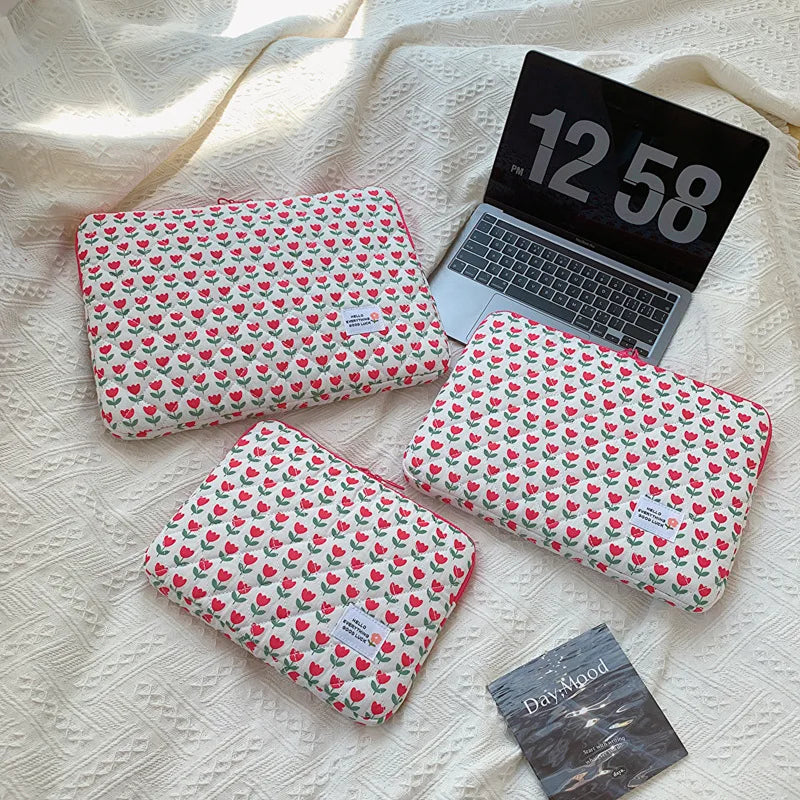 A floral printed laptop sleeve in red and green is shown next to an open laptop displaying the time 12:58.