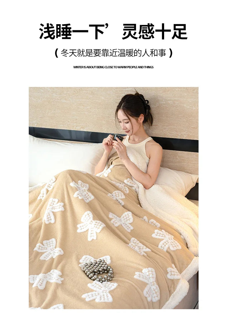 A woman is relaxing in bed with a beige plush jacquard throw blanket featuring white butterfly patterns.