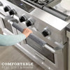 A hand is gripping a soft gray handle cover on a stainless steel appliance, emphasizing comfortable feel and warmth.