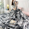 A gray gradient bubble fleece throw blanket draped over a person and spread out on a surface.