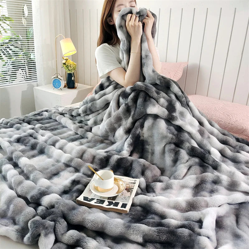A gray gradient bubble fleece throw blanket draped over a person and spread out on a surface.