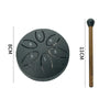 A black mini steel tongue drum with six tuning holes and a wooden mallet shown next to a measurement scale.