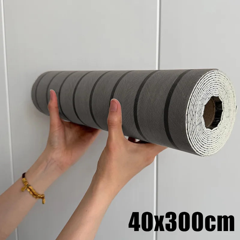 Hands are pulling a roll of gray self-adhesive wood grain wall panels for accent walls from a surface.