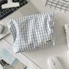 A light blue and white striped fabric makeup bag with floral embroidery resting on a white surface.