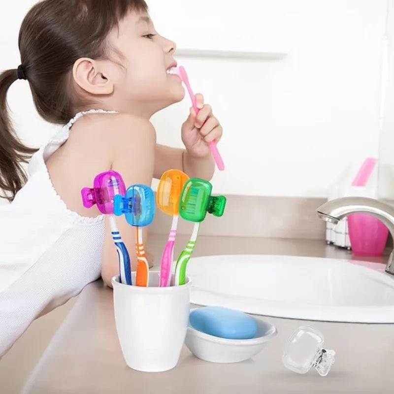 A child is using a pink toothbrush head cover while several colorful silicone brush heads are displayed in a white cup.