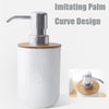 White bathroom soap dispenser with a chrome pump and a bamboo base, imitating a palm curve design.