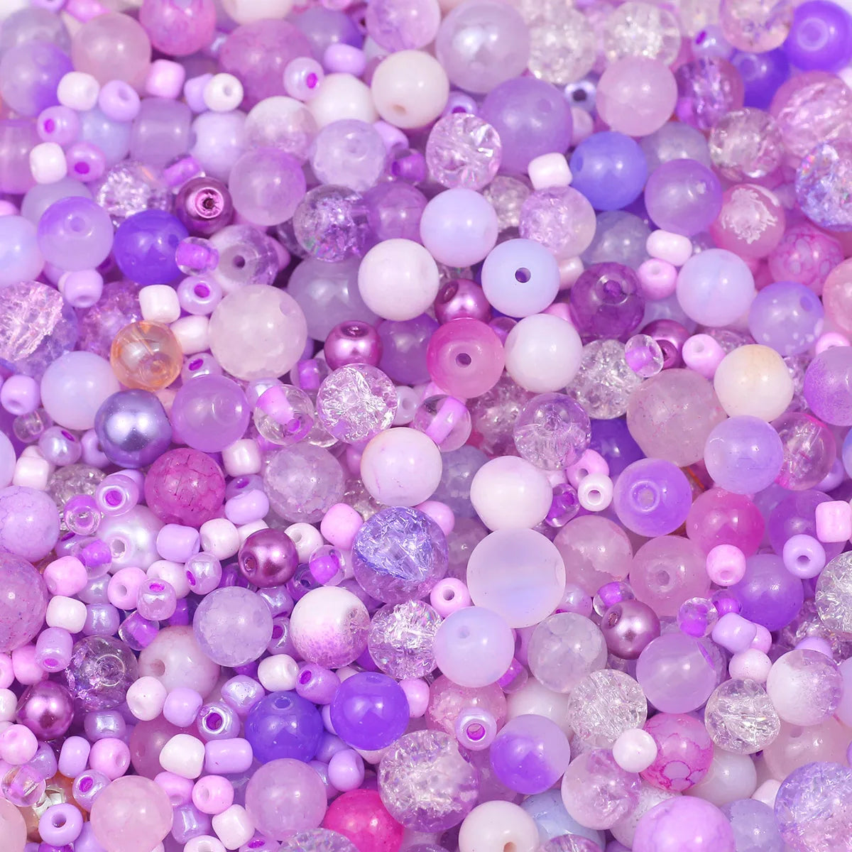 A close-up view of mixed sized glass beads in various shades of purple and pink for jewelry making