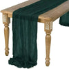 Dark green cotton gauze table runner draped over a rustic wooden table.