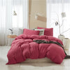 A pink duvet cover set with pom tassels is displayed on a bed in a bright room.