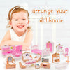A young girl smiles while posing with a pink and white dollhouse furniture set for pretend play.