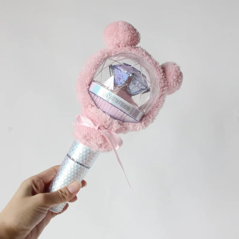 A hand holds a plush pink cover for a SEVENTEEN official light stick, featuring a clear dome and a purple crystal.