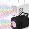 A black handheld bubble machine is shown blowing a large stream of iridescent, colorful bubbles toward a white box.