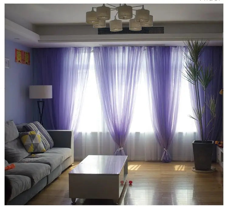 Purple sheer voile curtains hanging in a window with light filtering through.