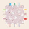 A pink baby sensory tag comfort blanket featuring white flamingos and hearts.