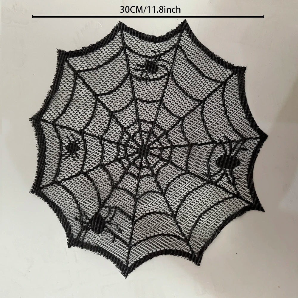 A black, intricate spider web design on a clear mesh material used as a Halloween table runner or placemat.