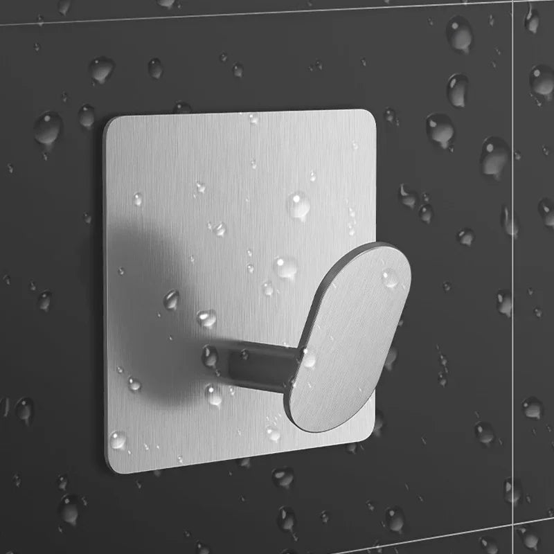 A silver adhesive stainless steel robe hook mounted on a dark surface with water droplets.