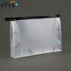 A transparent travel toiletry bag with a black zipper and hanging hooks is shown against a gray background.