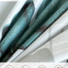 Close-up of a teal and grey watercolor floral microfiber fabric showing its soft texture and breathable qualities.