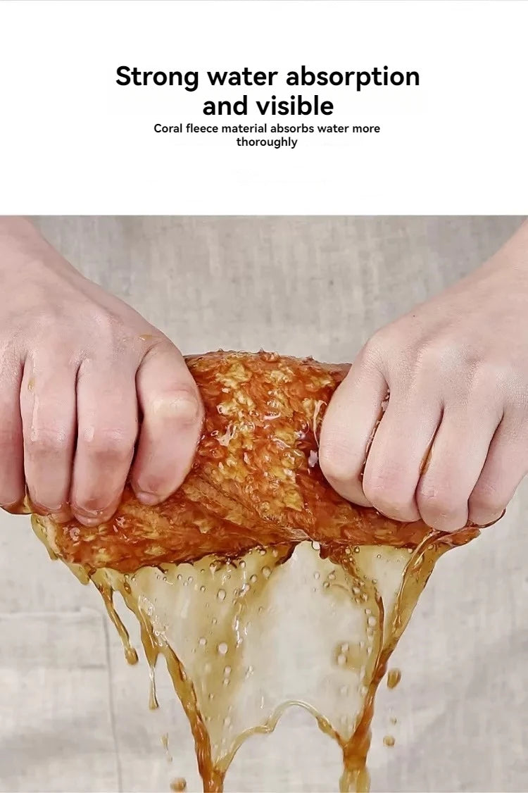 Hands are squeezing a piece of orange food, demonstrating the strong water absorption of a coral fleece material.