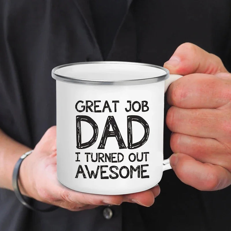 Une main tient une tasse à café en émail blanc avec l'inscription Great Job Dad I turned out Awesome.
