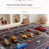 A dark play mat with various toy cars and vehicles laid out for a children's activity.