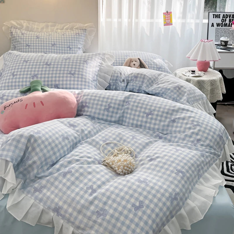 A light blue and white checkered duvet cover set with ruffled edges and floral embroidery displayed on a bed.