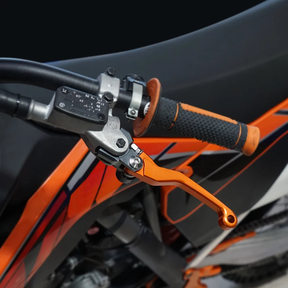 Close-up of an orange and black dirt bike handlebar featuring a silver brake and clutch lever set.